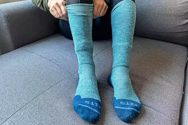 A person adjusting the Fits Light Ski Socks on their feet