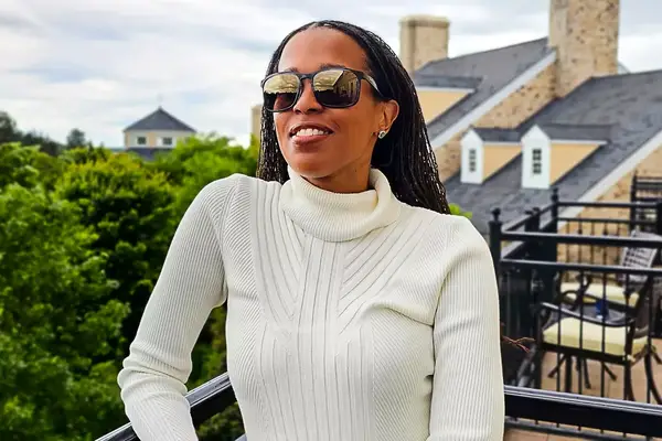 A person wearing Ray-Ban Chromance Sunglasses and a turtleneck sweater on an outdoor balcony