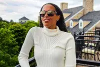 A person wearing Ray-Ban Chromance Sunglasses and a turtleneck sweater on an outdoor balcony