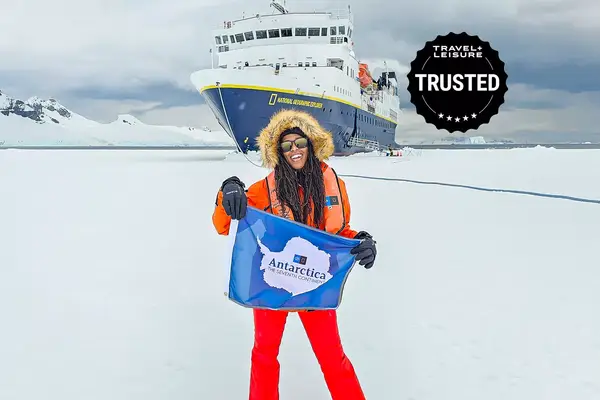 Woman stands in front of ship in Antarctica