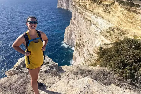 Person wearing the Smartwool tank top on a viewpoint of the ocean and cliffs