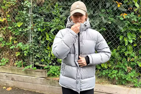 A person zips up the Quince Responsible Down Long Puffer Jacket