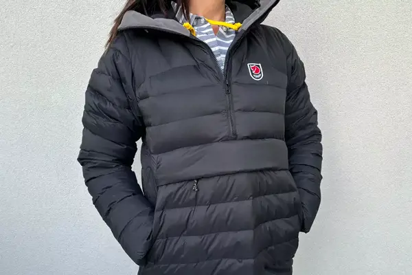 A person wearing the Fjallraven Expedition Pack Down Anorak in front of a white wall with their hands in their pockets