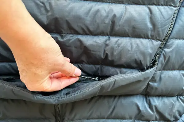 A hand on a zipper of the Fjallraven Expedition Pack Down Anorak