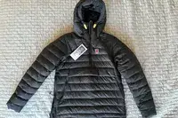 The Fjallraven Expedition Pack Down Anorak with tags on a fabric background