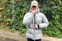 A person zips up the Quince Responsible Down Long Puffer Jacket