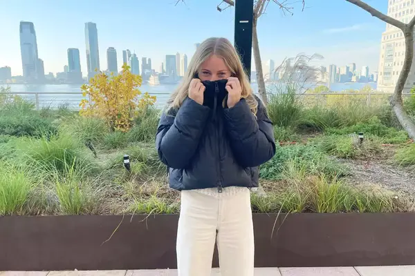A person wearing the Canada Goose Garnet Cropped Puffer in front of a city skyline