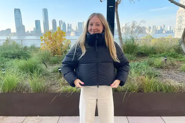 A person wearing the Canada Goose Garnet Cropped Puffer in front of a city skyline