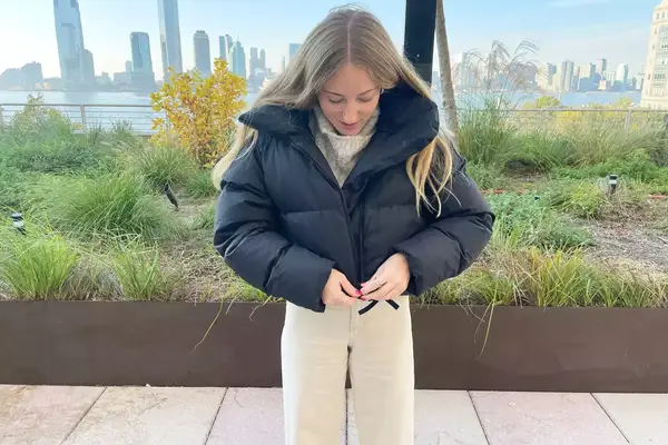A person zipping up the Canada Goose Garnet Cropped Puffer jacket