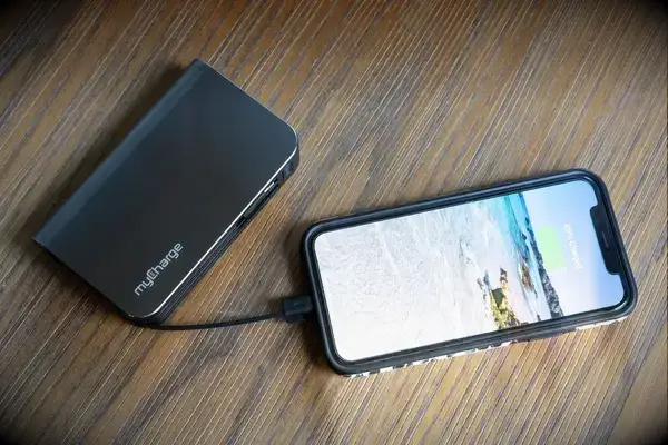 The myCharge Fast Charging Portable Charger charging a phone on a wooden surface