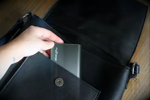 A hand placing the myCharge Fast Charging Portable Charger into a bag