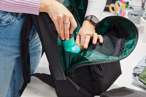 Hands pulling a water bottle from the Troubadour Orbis 1-Pocket Backpack