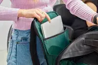 Hand putting a laptop into the Troubadour Orbis 1-Pocket Backpack