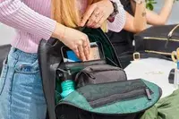 Hands pulling a tablet from the Troubadour Orbis 1-Pocket Backpack