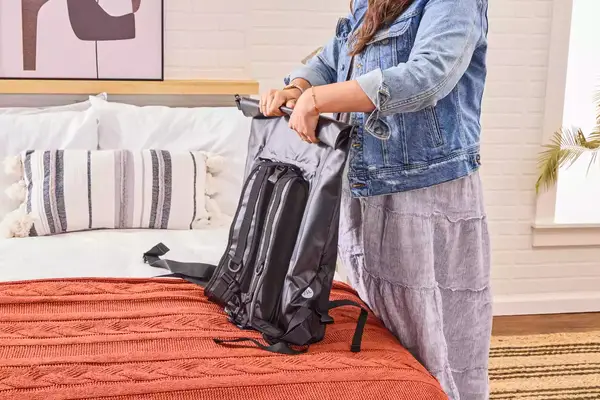 A person rolls up the Earth Pak Summit Dry Bag Backpack