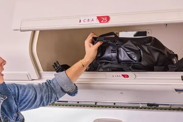 The Earth Pak Summit Dry Bag Backpack is placed into an overhead compartment