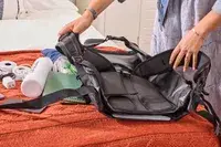A person packs the Earth Pak Summit Dry Bag Backpack