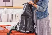 A person packs the Earth Pak Summit Dry Bag Backpack