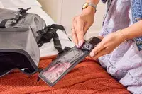 A person adjusts the closure on the Earth Pak Summit Dry Bag Backpack