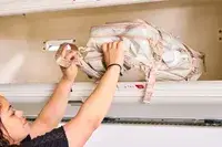 A person places the Calpak Terra 26L Laptop Duffel Backpack into an overhead compartment