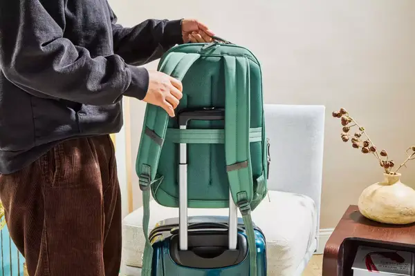 A person placing the Samsonite Elevation Plus Backpack on top of a suitcase
