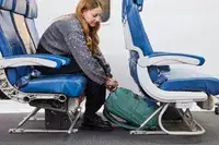 A person placing the Samsonite Elevation Plus Backpack under an airplane seat