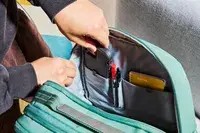 Hands placing a phone inside of the Samsonite Elevation Plus Backpack