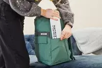 Hands placing a water bottle in the side pouch of the Samsonite Elevation Plus Backpack 