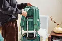 A person placing the Samsonite Elevation Plus Backpack on top of a suitcase