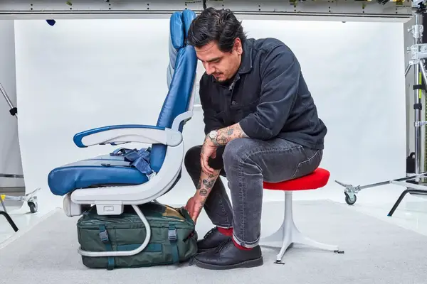 Person placing Away Convertible Backpack underneath airplane seat.