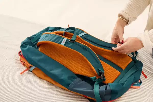 A person adjusts the straps on the Cotopaxi Allpa 42L Travel Pack