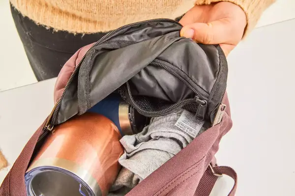 A person adjusts the waist strap on the Cotopaxi Allpa 42L Travel Pack