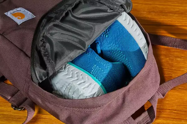 A person opens the pocket on the Cotopaxi Allpa 42L Travel Pack