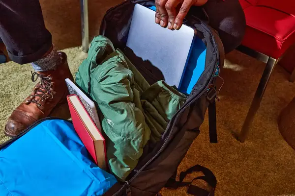 Hand putting laptop into Kühl Eskape 25 Backpack