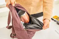 A person secures a strap on the Cotopaxi Allpa 42L Travel Pack