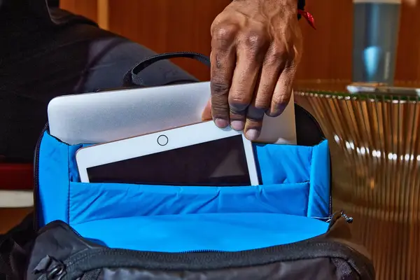 Hand holding an tablet inside of an inner pocket in the Kühl Eskape 25 Backpack