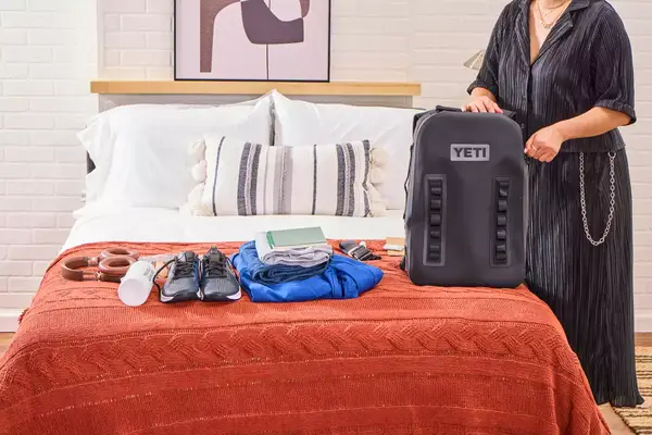 A person zips up the Yeti Panga 28L Waterproof Backpack