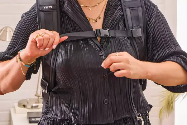 A person adjusts the straps on the Yeti Panga 28L Waterproof Backpack