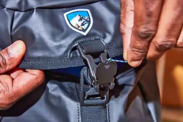 Close-up of hands unbuckling the Kühl Eskape 25 Backpack