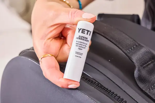 A person holds up a stick of Yeti Zipper Lubricant that came with the Yeti Panga 28L Waterproof Backpack