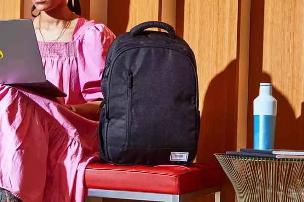 Person sitting next to the Solo Re:Define Backpack on a red leather bench