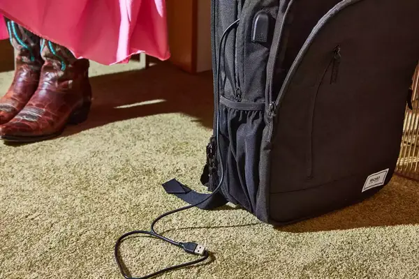 Solo Re:Define Backpack displayed on a carpet with a charging cable hanging out