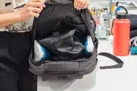 Hands holding open the Solo Re:Define Backpack to display the contents