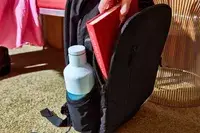 Hand adding a book to the Solo Re:Define Backpack