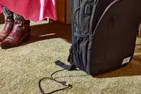 Solo Re:Define Backpack displayed on a carpet with a charging cable hanging out