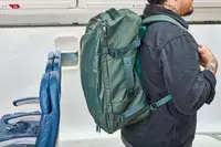 A person wears the Away The Outdoor Convertible Backpack 45L next to airplane seats