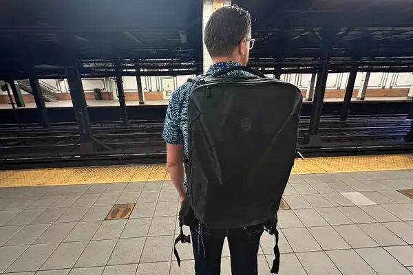 Man wearing the Tortuga Travel Backpack 40L while standing on a subway platform