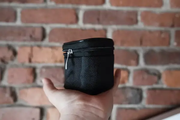 A hand holding the EPICKA Universal Travel Adapter travel case in front of a brick wall