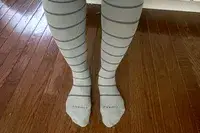 Comrad Knee High Compression Socks On Persons Feet Standing On Hardwood Floor