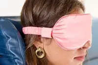 Close up of the side of a person wearing the Slip Lovely Lashes Contour Sleep Mask on a plane